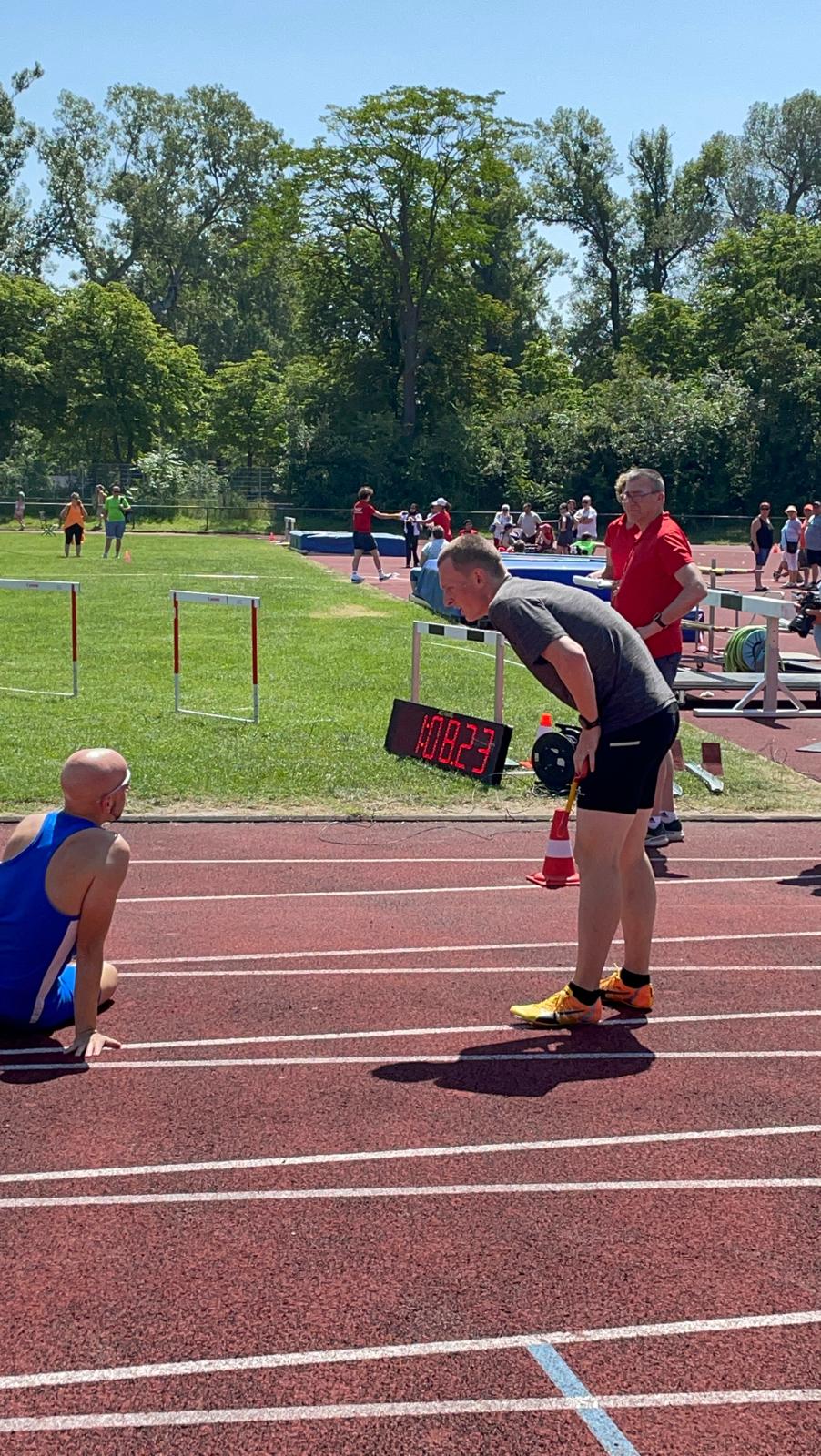 In the finish of the 400m race before the time display showing 68.23seconds. My Guide leaning over to me sitting on the floor after my fall after the finish line.