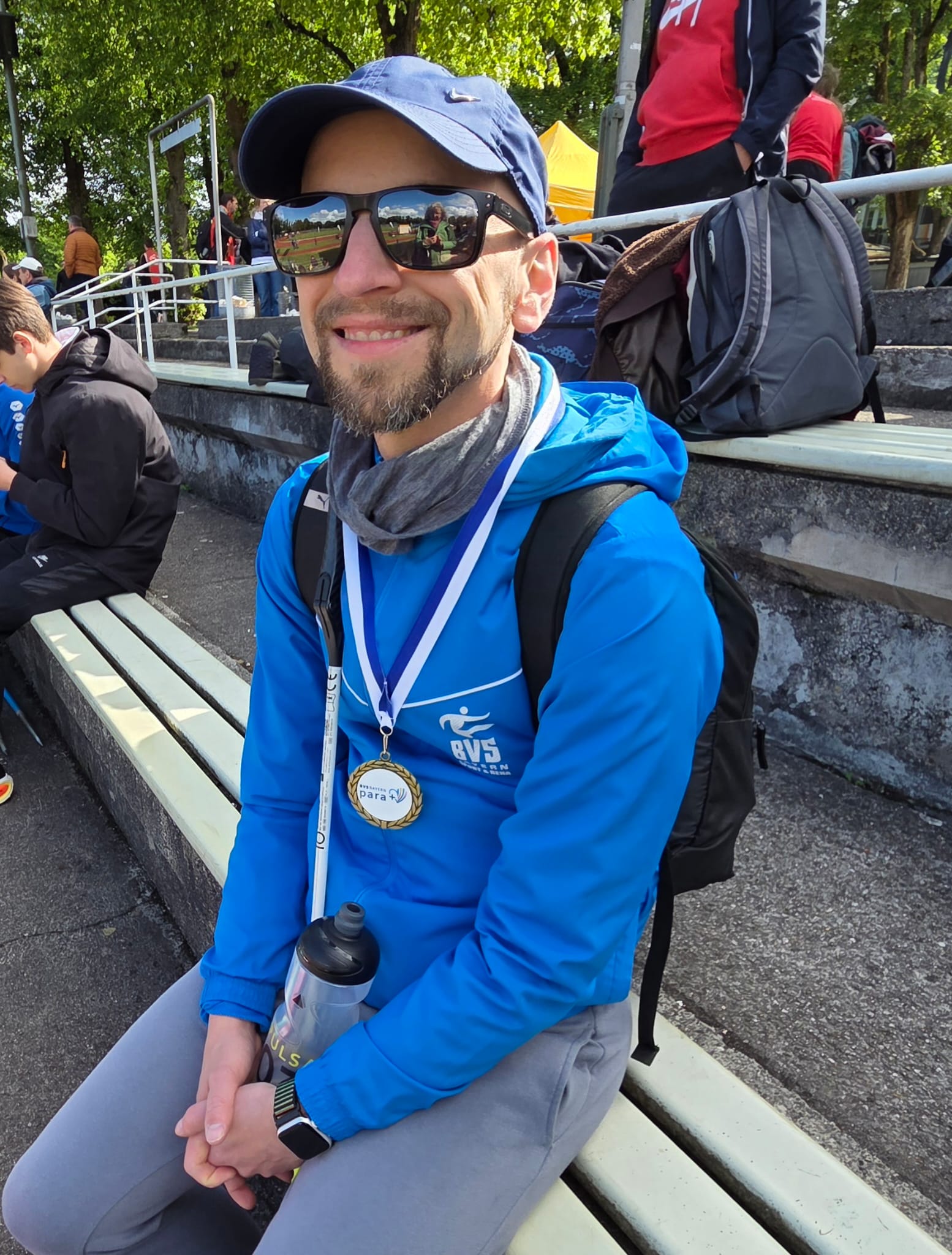 Stefan sitting on a bench in his BVS Bayern hoodie with the gold medal around his neck.